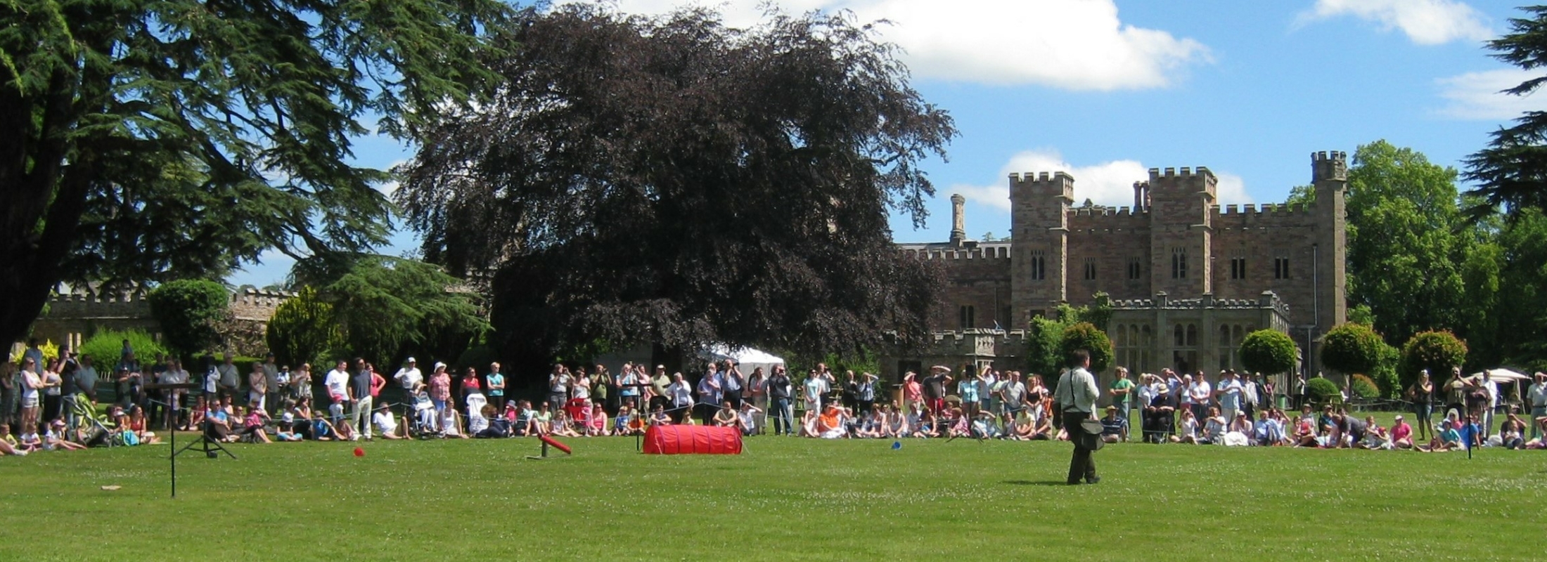 A crowd of people sitting on the grass in front of Hampton Court Castle