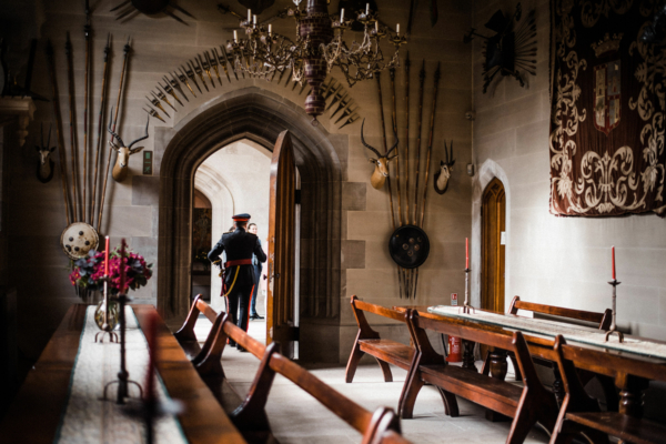 Groom in Guards outfit walking out of door in ornate hall