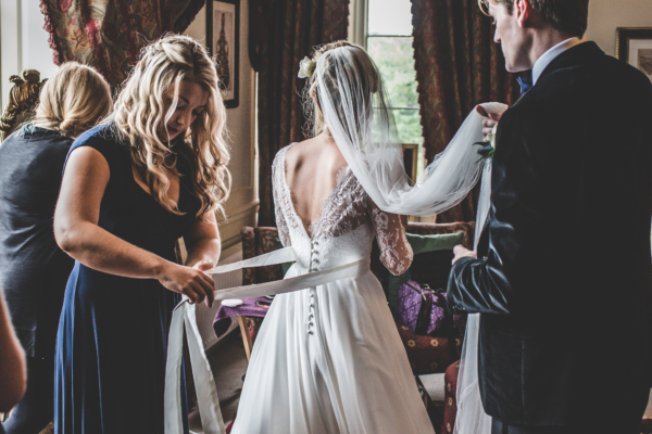 A bride getting dressed, assisted by her friends