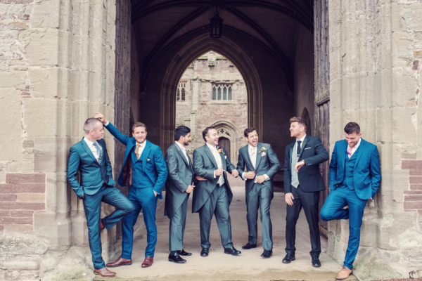 A groom and his groomsmen laughing in a castle doorway