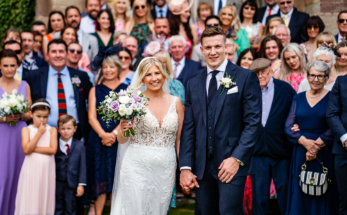 Couple pose for photo in front of wedding guests on south lawns