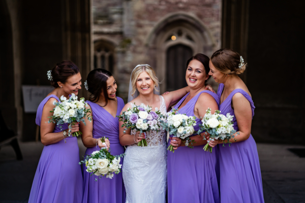 Bride smiles for photo with bridesmaids in draw through